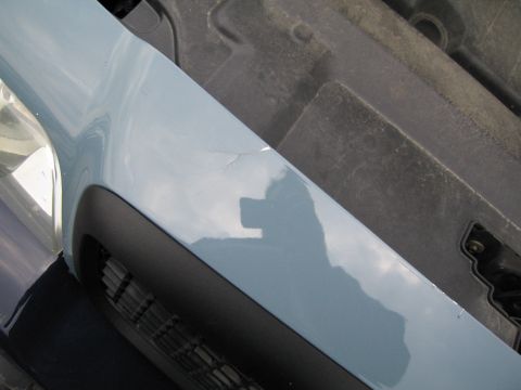 1991 Ford LTD Crown Victoria - Close-up of a light blue fender showing a crack in the paint and the photographer's reflection.