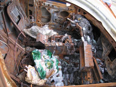 1991 Ford LTD Crown Victoria - The interior of a car is heavily damaged by fire, with melted components and debris scattered throughout.