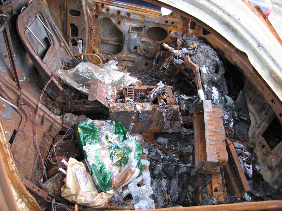 Interior of a severely burned car, showing melted dashboard and debris