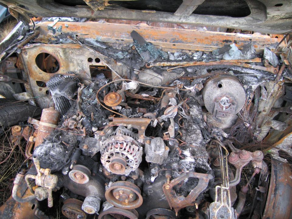 Burnt engine compartment with melted wires and rusted metal components
