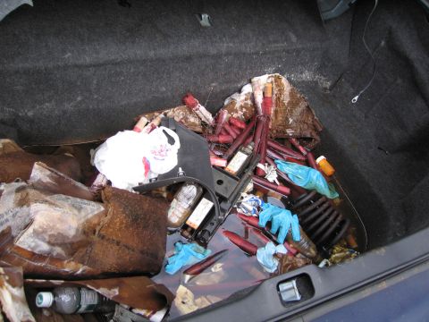 1991 Ford LTD Crown Victoria - The trunk of a vehicle is filled with various debris, including red tubes, plastic bags, and a water bottle, suggesting it is not in good c…