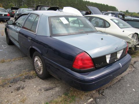 1991 Ford LTD Crown Victoria - This Ford Crown Victoria has a dark blue lower body and a light blue upper body, parked in a junkyard with other vehicles.