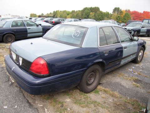 1991 Ford LTD Crown Victoria - A two-tone police car with dark blue and light blue panels sits in a junkyard.
