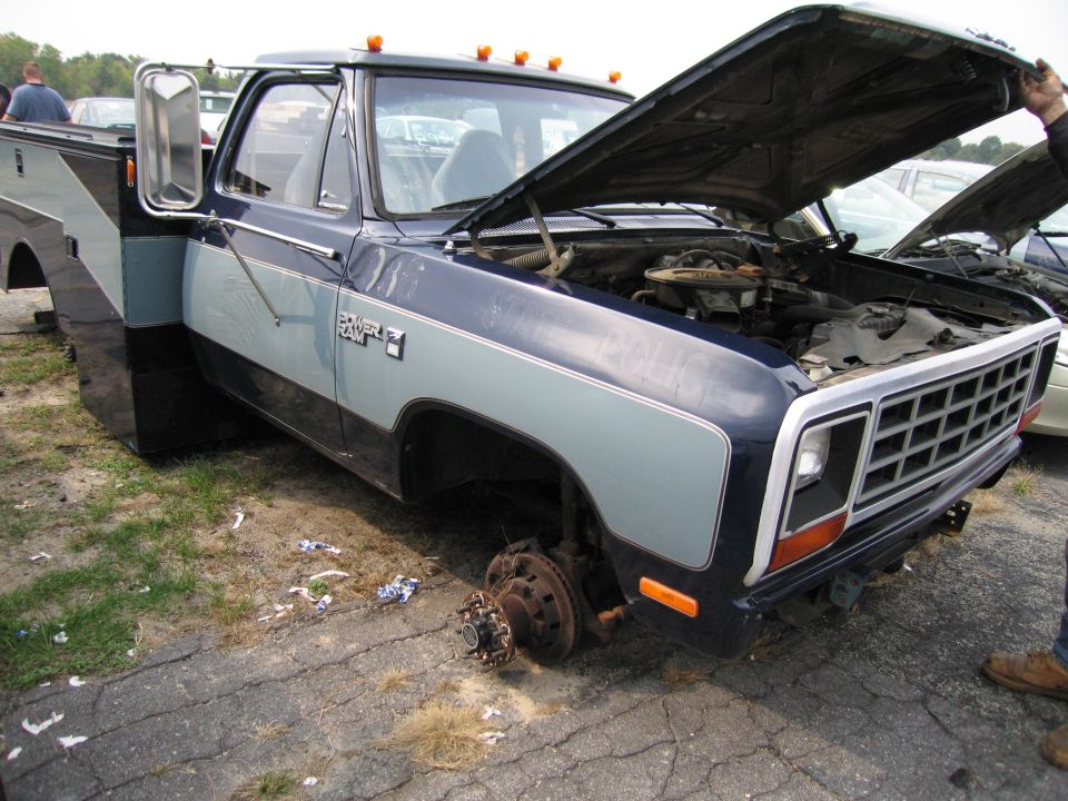 Dodge Ram pickup truck, hood open, front wheels missing, dual rear wheels visible on the passenger side