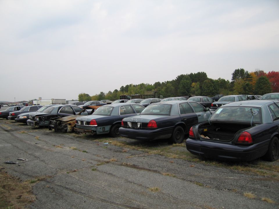 Dark blue 1991 Ford Crown Victoria LTD sedan in a junkyard, rear quarter view, trunk open