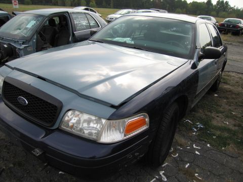 1991 Ford LTD Crown Victoria - A Ford Crown Victoria sits in a junkyard, its hood propped open, with another vehicle in the background.