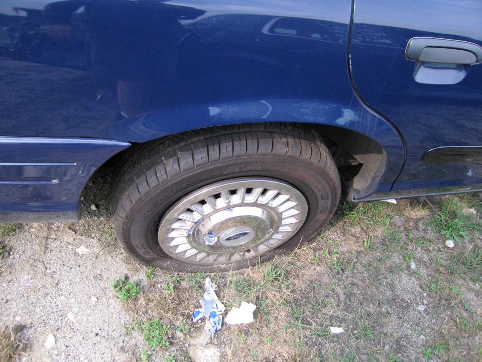 1991 Ford Crown Victoria LTD rear wheel with chrome hubcap and blue sedan door