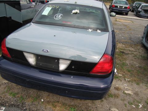 1991 Ford LTD Crown Victoria - A two-tone Ford Crown Victoria sits in a lot with other vehicles. The rear window has handwritten numbers on it.