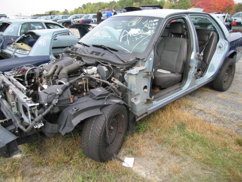 1991 Ford LTD Crown Victoria - This heavily damaged sedan sits in a junkyard, missing its front end and showing its interior.