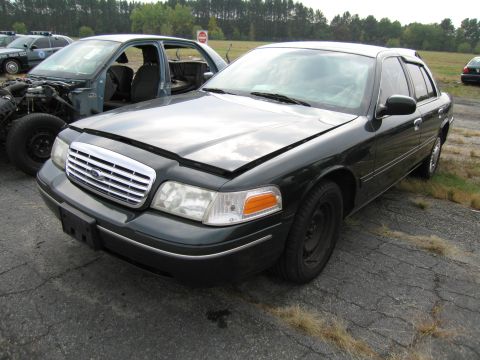 1991 Ford LTD Crown Victoria - A dark green Ford Crown Victoria sits in a lot, hood ajar, with another vehicle partially visible beside it.