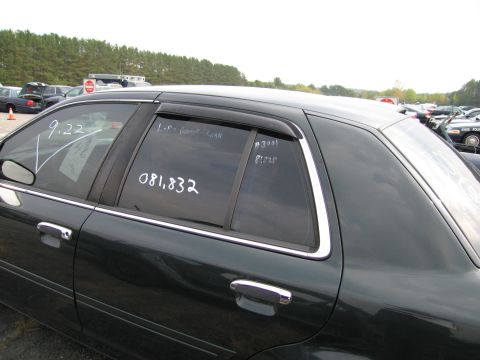 1991 Ford LTD Crown Victoria - A dark green sedan is parked in an outdoor lot with other vehicles, showing handwritten notes on its windows.