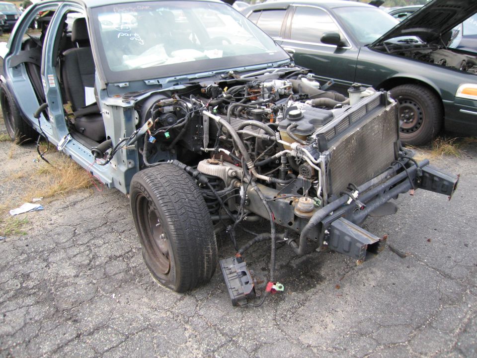 1991 Ford Crown Victoria LTD stripped down, engine exposed, front bumper removed, parked next to another car