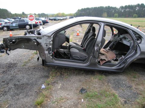 1991 Ford LTD Crown Victoria - A stripped-down gray sedan sits in a lot with other vehicles and a 'Do Not Enter' sign.