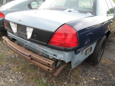 1991 Ford LTD Crown Victoria - The rear of a Ford Crown Victoria shows damage and modifications, with a second vehicle visible in the background.