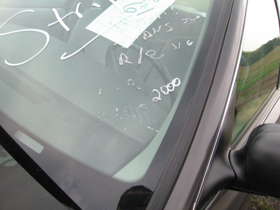 Car windshield with white writing and a white sticker. Writing includes 'Str-', 'R/R', 'V/G', and '2000'