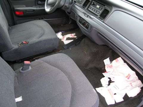 1991 Ford LTD Crown Victoria - The interior of a car shows a messy floor with several Dunkin' Donuts bags scattered around.