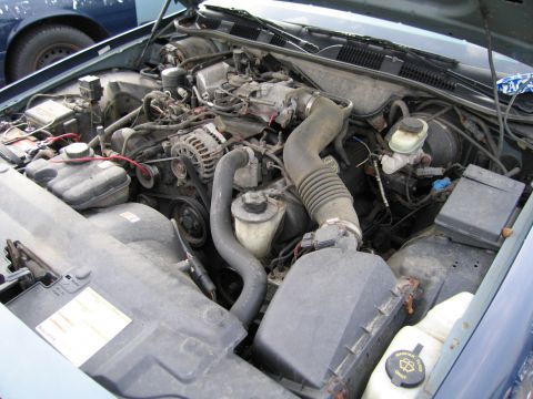 1991 Ford LTD Crown Victoria - The engine compartment of a vehicle, showing various mechanical parts and wiring.