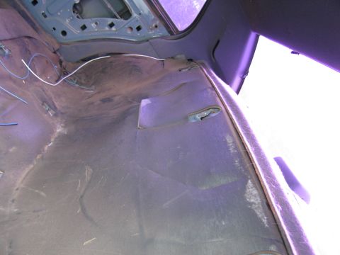 1991 Ford LTD Crown Victoria - The interior of a car shows exposed wiring and the bare frame after the carpet has been removed.