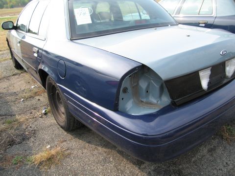 1991 Ford LTD Crown Victoria - A two-tone Ford Crown Victoria is parked outdoors, showing damage to its rear.