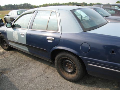 1991 Ford LTD Crown Victoria - This two-tone vehicle, possibly a former police car, is seen from the side with multiple vehicles in the background.