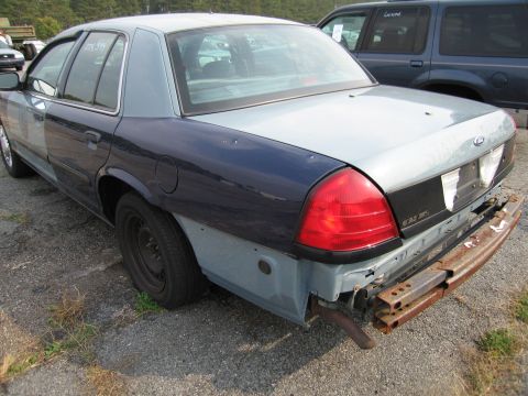 1991 Ford LTD Crown Victoria - This two-tone sedan shows significant rear-end damage, with a detached bumper and exposed frame components.