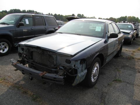 1991 Ford LTD Crown Victoria - A damaged Ford Crown Victoria sits in a junkyard, missing its front end components.