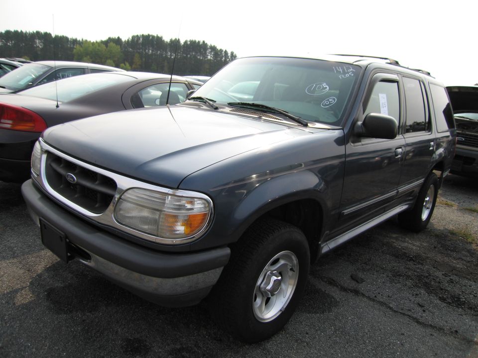 Dark gray Ford Explorer parked in a lot with other cars. White writing on windshield