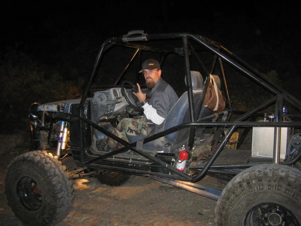 Man in a roll cage buggy with large tires and a fire extinguisher