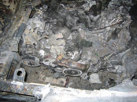 1994 Ford Bronco - Engine compartment severely damaged by fire, showing melted and charred components.
