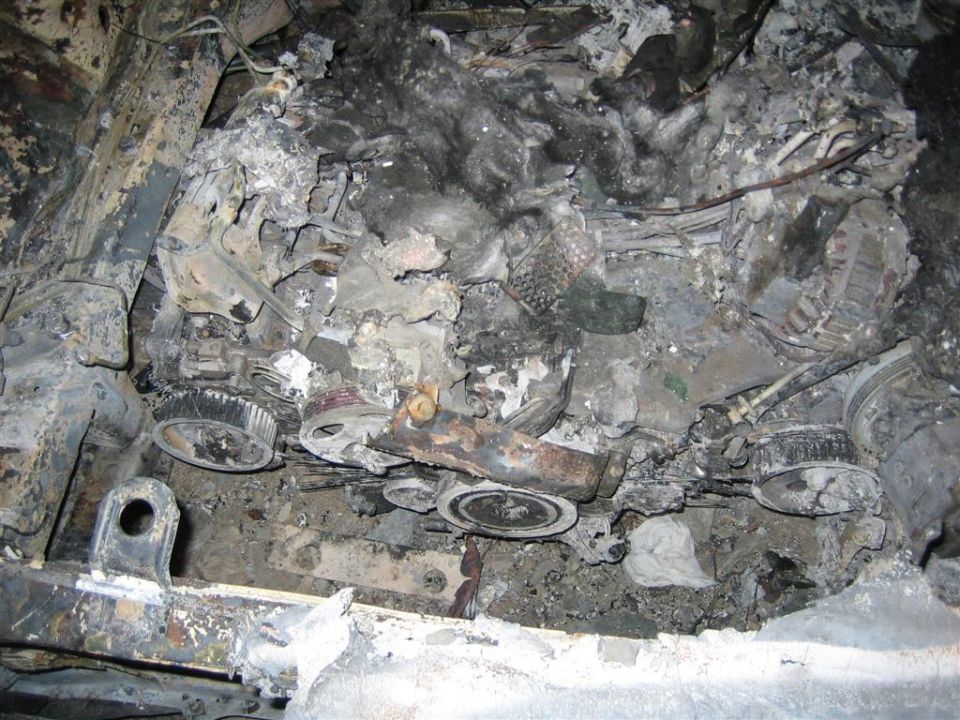 Burnt engine parts, pulleys, and wiring after a fire