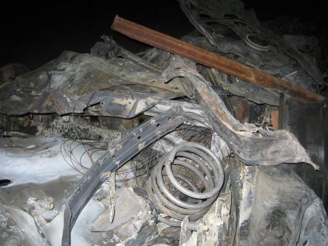 1994 Ford Bronco - This is a close-up view of heavily damaged and burnt vehicle wreckage, showing twisted metal and debris.
