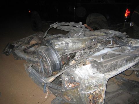 1994 Ford Bronco - The severely damaged remains of a vehicle are visible, with twisted metal and a detached wheel assembly dominating the scene.
