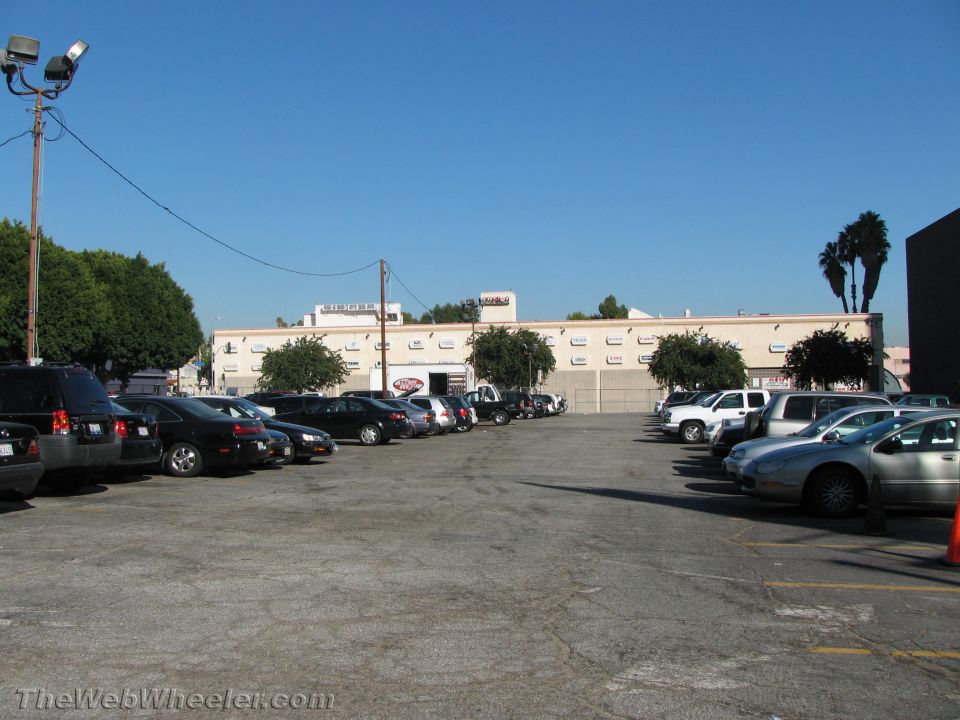 Parking lot scene with numerous cars parked under a clear blue sky