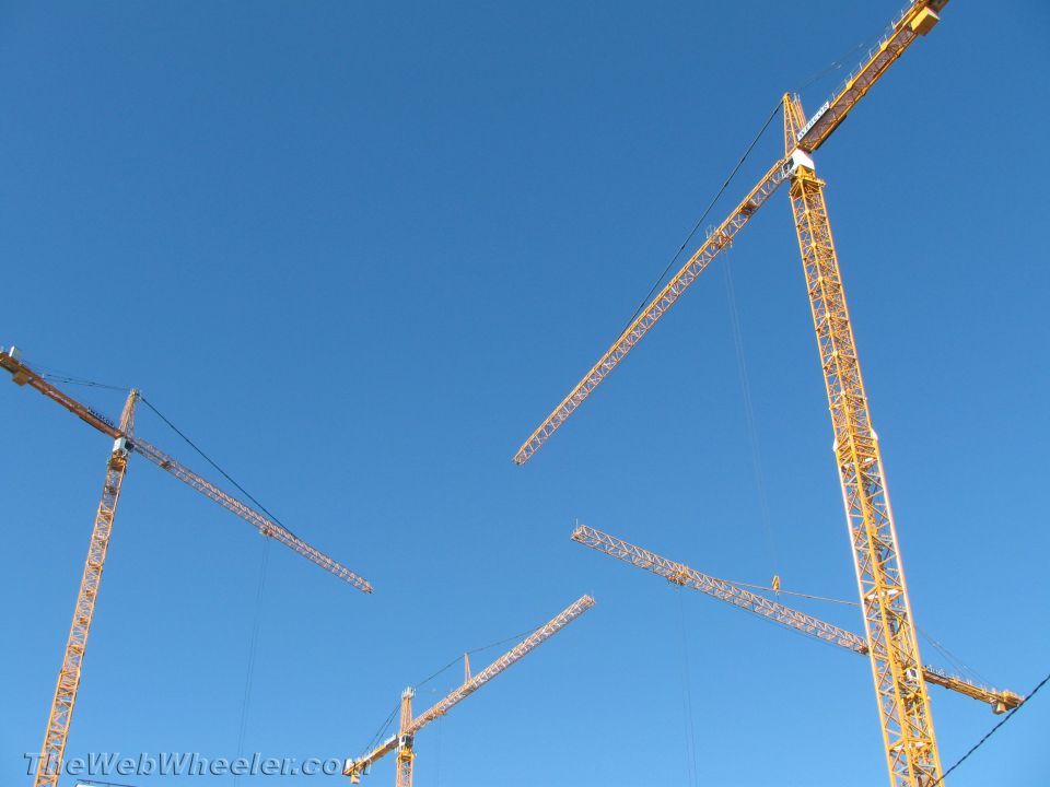 Multiple yellow construction cranes against a clear blue sky