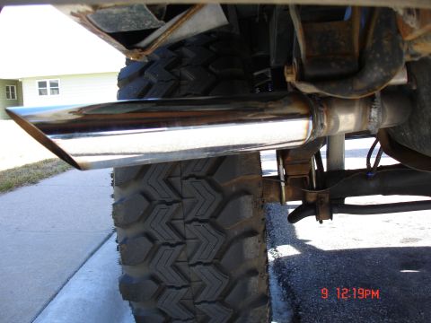 1979 Ford Bronco - Close-up of a chrome exhaust tip and a large off-road tire on a vehicle.
