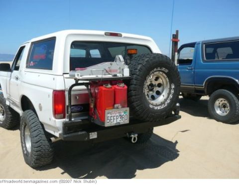 1994 Ford Bronco - Rear view of a white 1994 Ford Bronco equipped with a spare tire, jerry cans, and a winch mounted on the bumper.