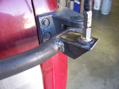 1991 Ford Bronco - Close-up of a custom CB antenna mount, welded to a bracket attached to a red vehicle's door hinge area.