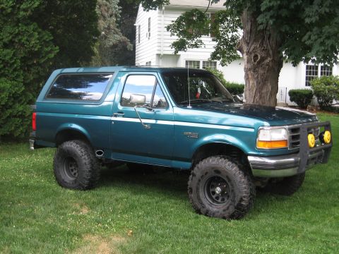 1996 Ford Bronco - Teal 1996 Ford Bronco with aftermarket bumper and large tires sits on a lawn.