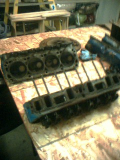 1985 Ford Crown Victoria LTD - Engine parts are laid out on a workbench, possibly for repair or rebuilding.