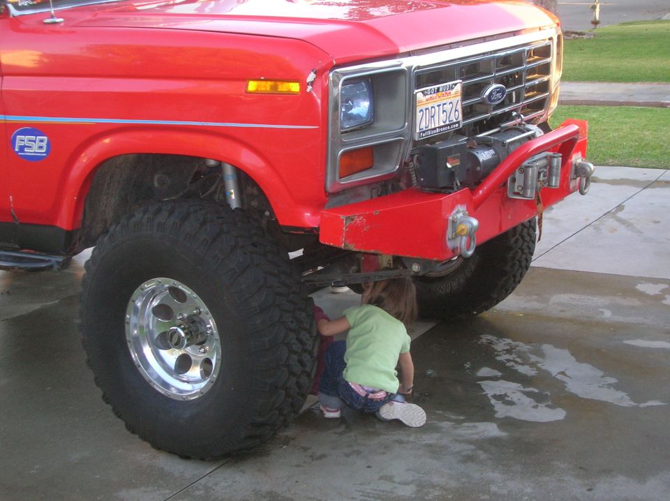 Red Ford Bronco with a custom bumper and winch, two kids are looking underneath it