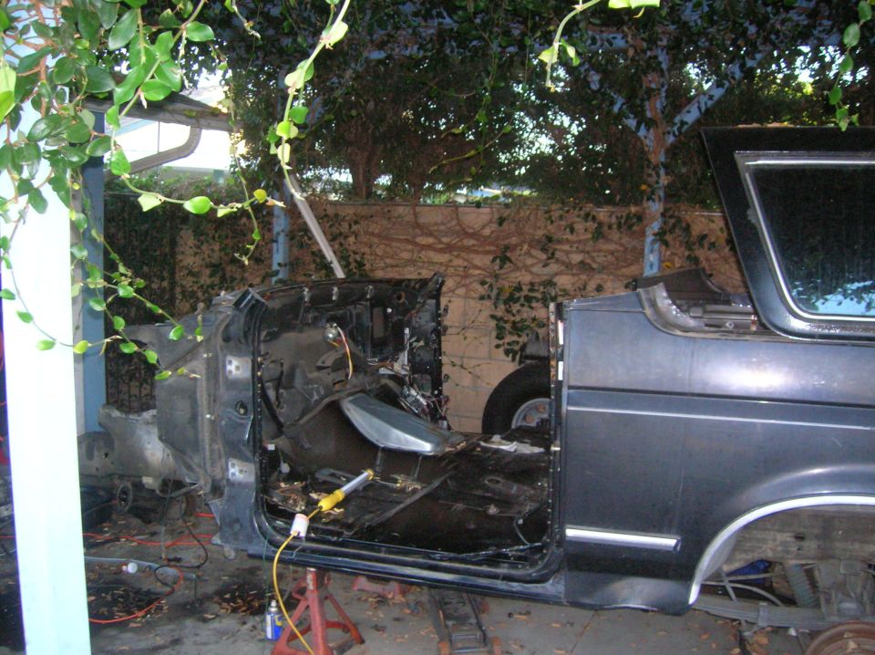 Vehicle interior disassembled, showing floor and door panel. Supported by jack stands