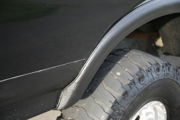 Closeup of black fender flare edge above an all-terrain tire
