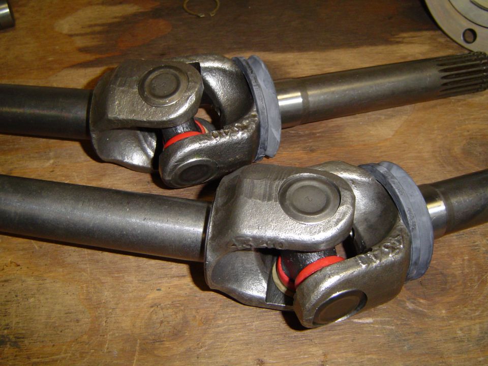 Two front axle shafts with U-joints and red and white seals
