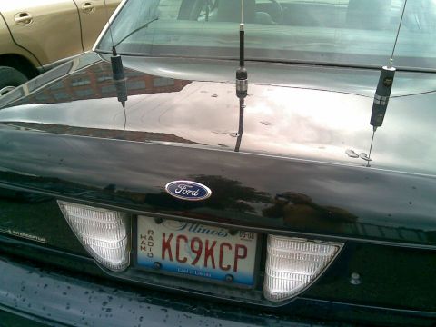 2003 Ford Crown Victoria - Rear view of a black 2003 Ford Crown Victoria, equipped with multiple antennas and an Illinois license plate.