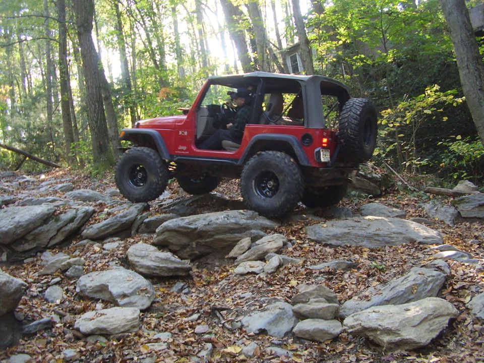 Red Jeep Wrangler navigating a rocky trail, 2003