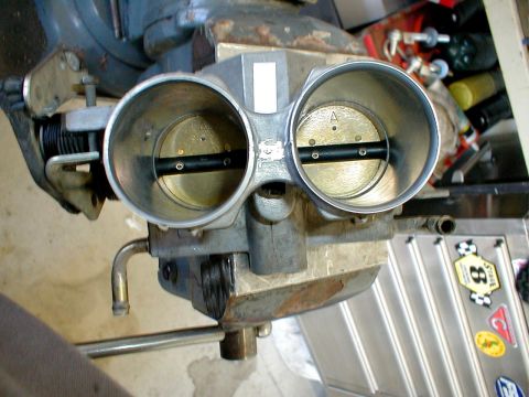1996 Ford Bronco - Close-up of a dual throttle body, held in a vise for inspection or work.