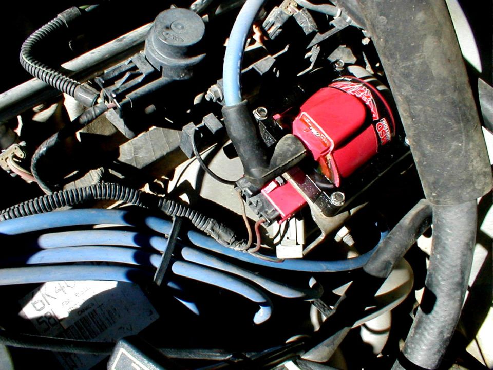 Close-up of a red MSD ignition coil and blue spark plug wires in an engine bay