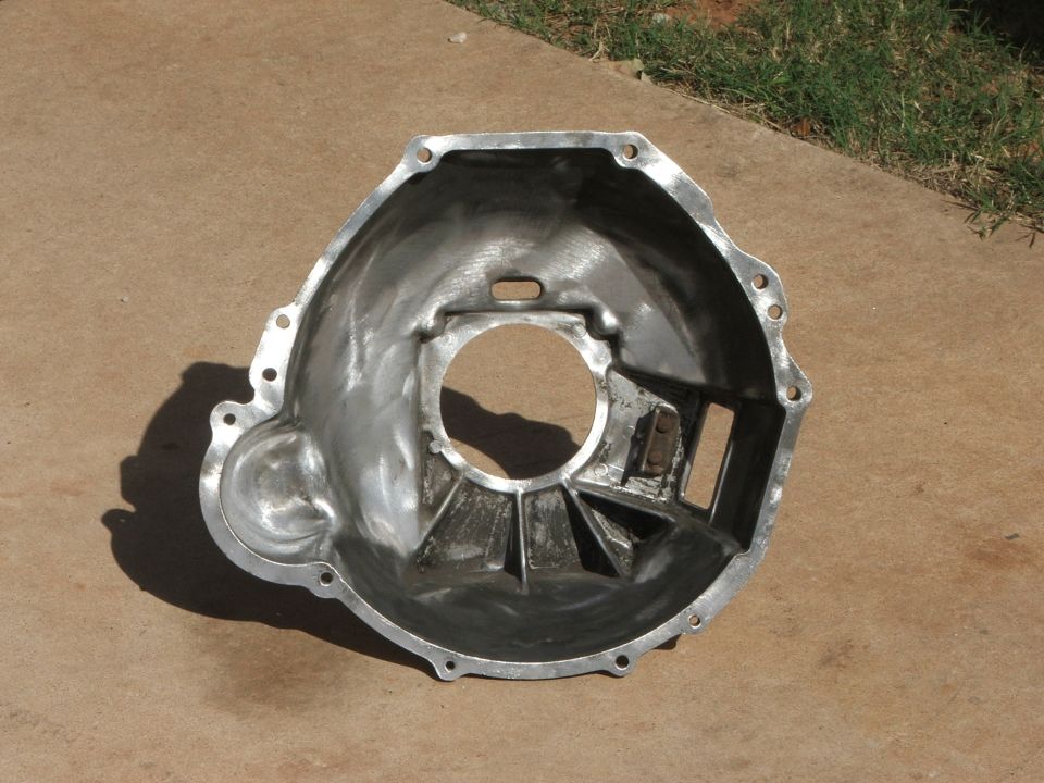 Aluminum bell housing with mounting holes and internal bracing, resting on concrete