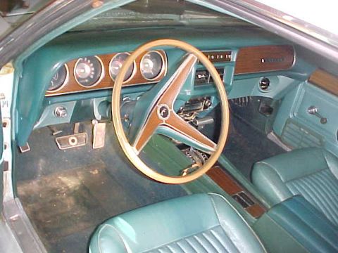 1969 Ford Torino - The interior of a 1969 Mercury Cougar features teal vinyl seats and a woodgrain dashboard panel.