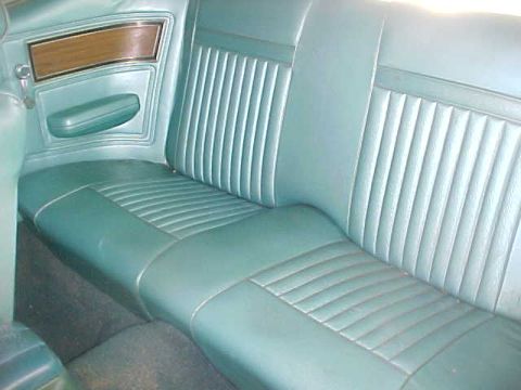 1969 Ford Torino - The interior features a teal bench seat with pleated upholstery and a wood-accented door panel.